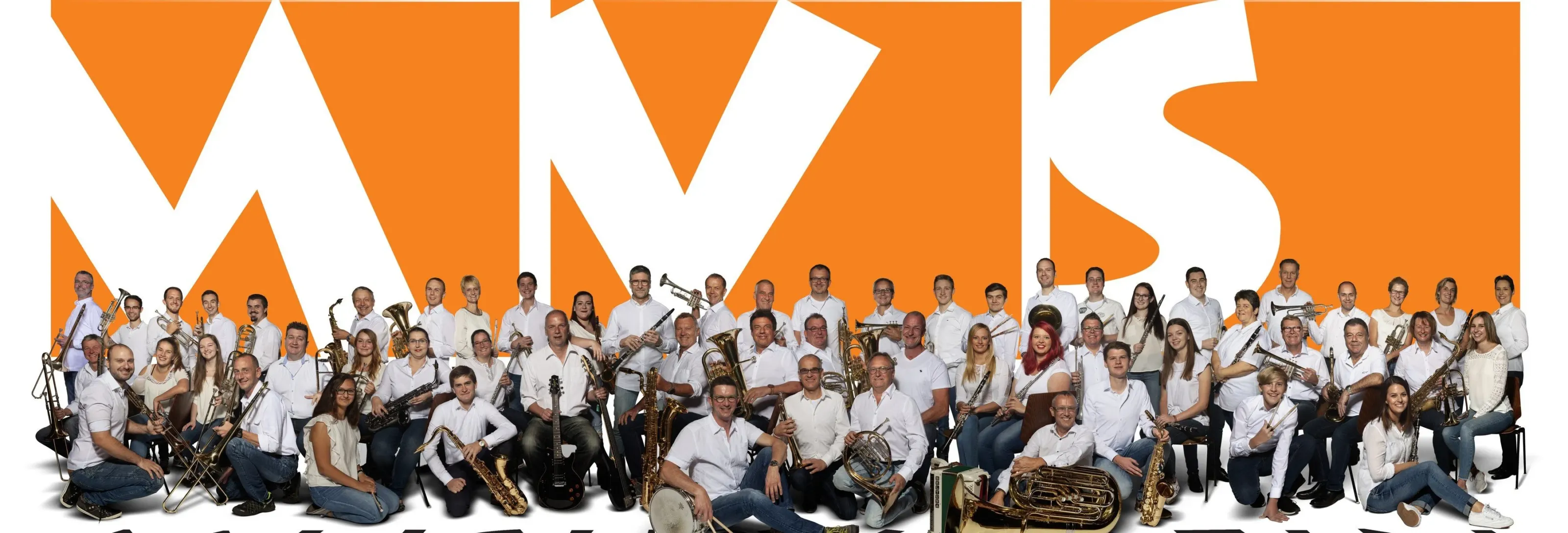 Das gesamte Blasorchester des Musikvereins Söllingen mit Instrumenten vor dem großen orangen MVS-Vereinslogo