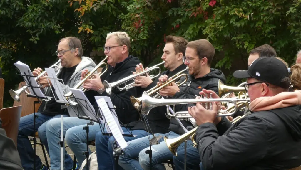 Eine Reihe Trompeterinnen und Trompeter unterschiedlichen Alters spielt nebeneinander im Freien