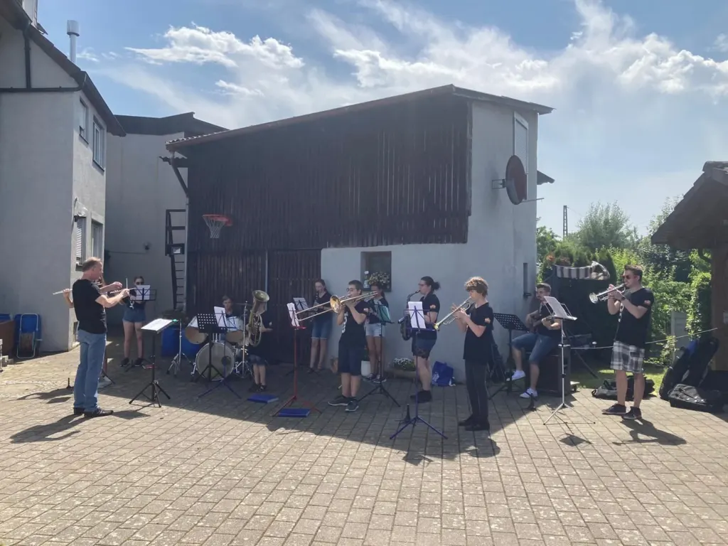 Das Jugendorchester des MVS beim Platzkonzert im Hof, der Dirigent vor dem Halbkreis der jungen Musikerinnen und Musiker